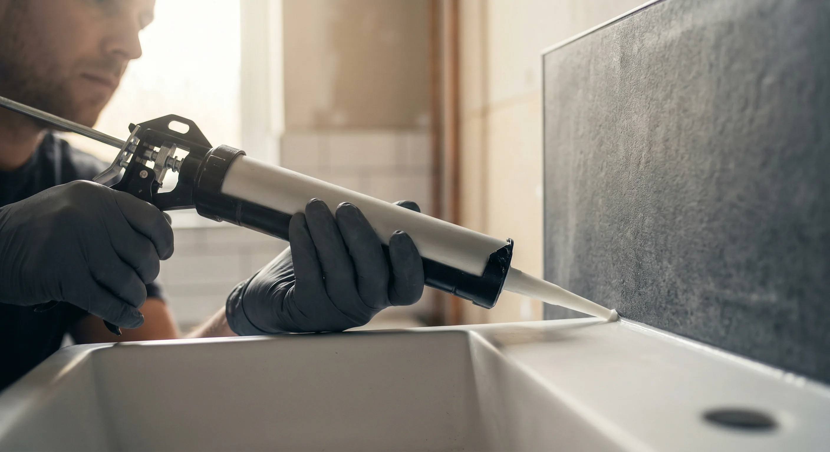 Badsanierung Teilsanierung – Topallaj Haustechnik GmbH Handwerker versiegelt Badewanne mit Silikon bei Teilsanierung – Topallaj Haustechnik